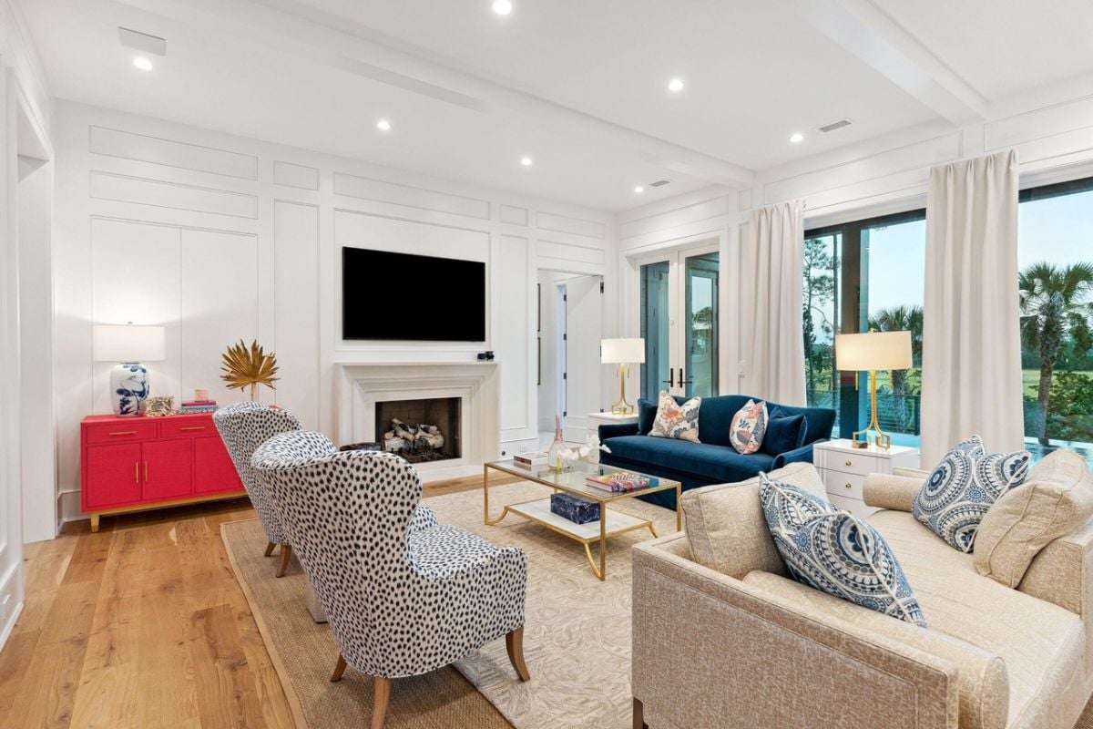 Living room with couches, a large rug, TV, glass wall windows and a fireplace.