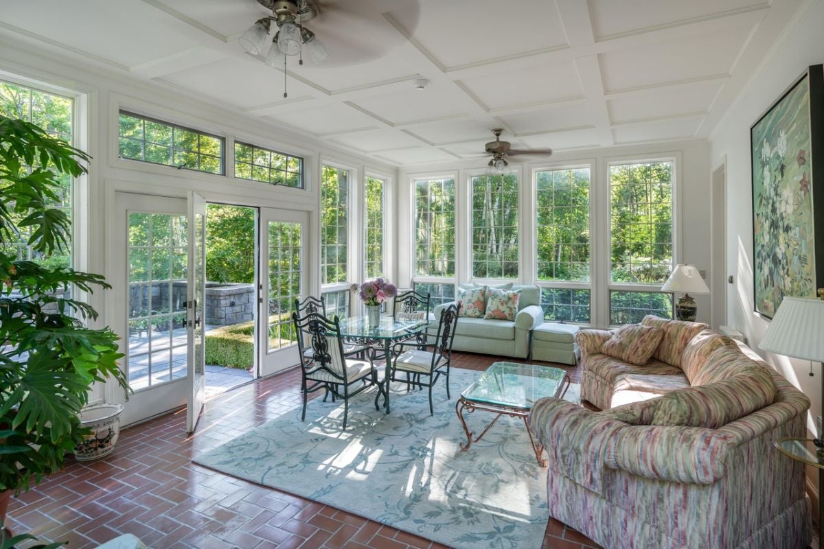 Living room with couches, glass walls, glass door and a large rug.