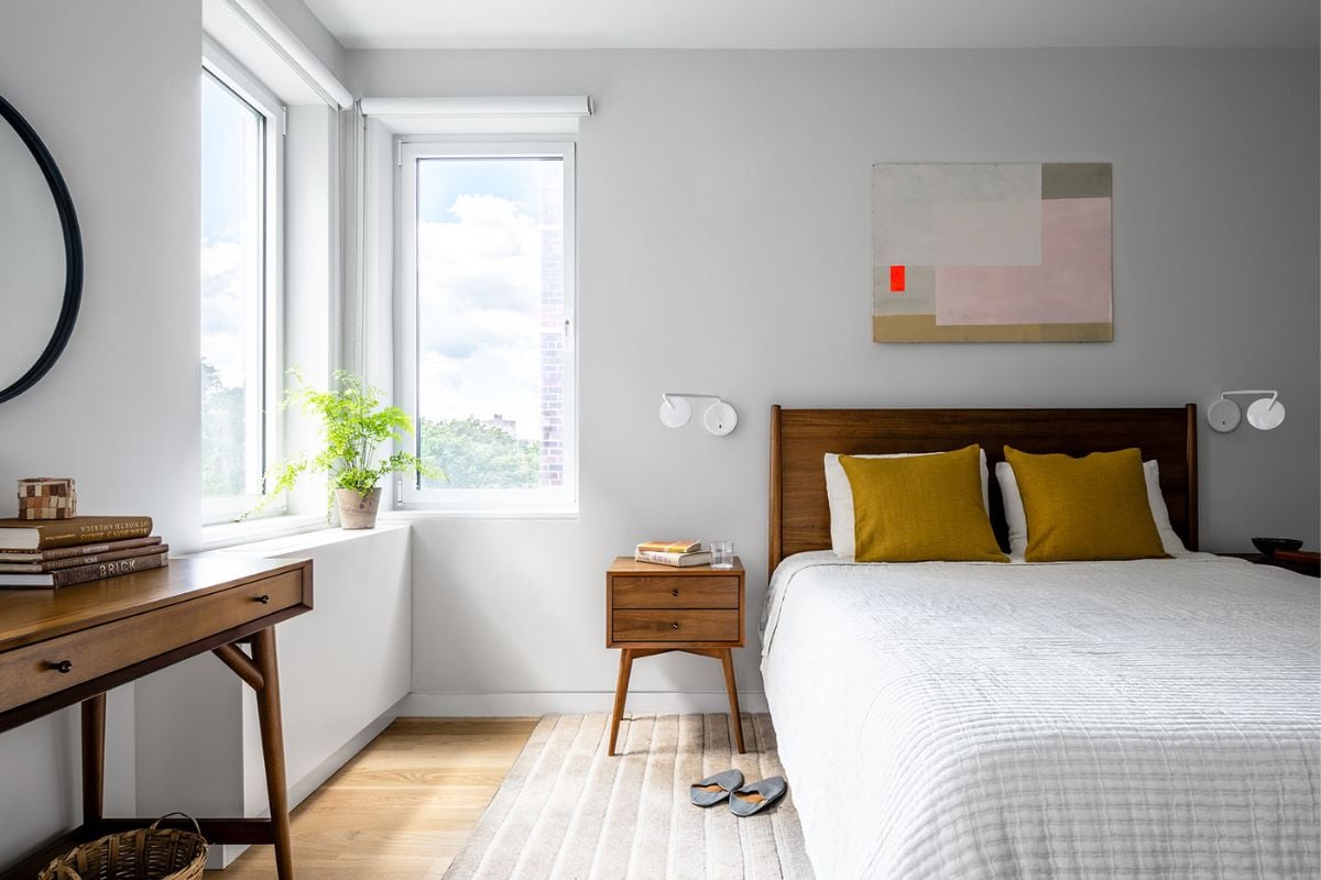 Abedroom with desk and a glass window that allows sunlight to pass through