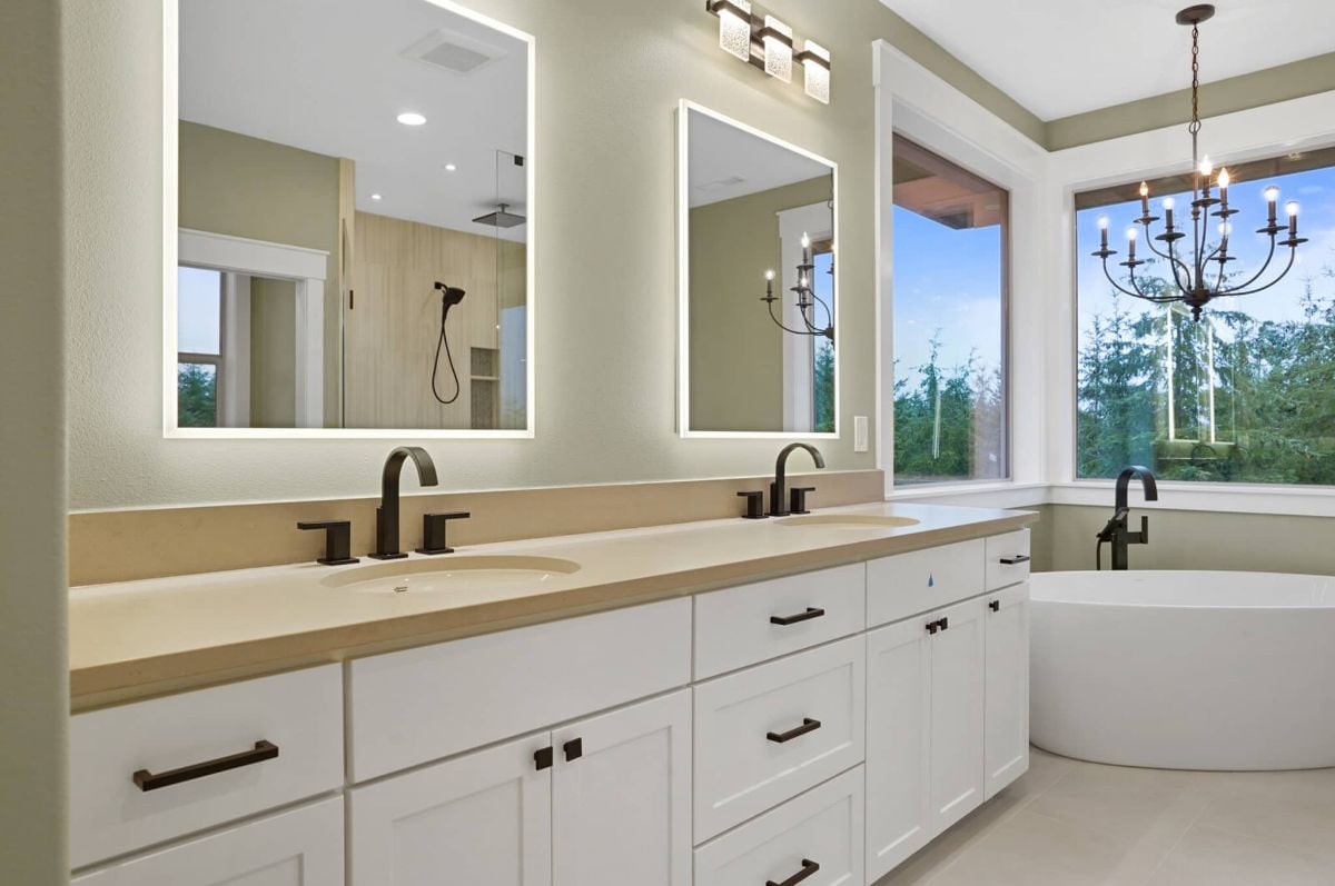 Bathroom with a sink, soaking tub, mirrors and custom lights.