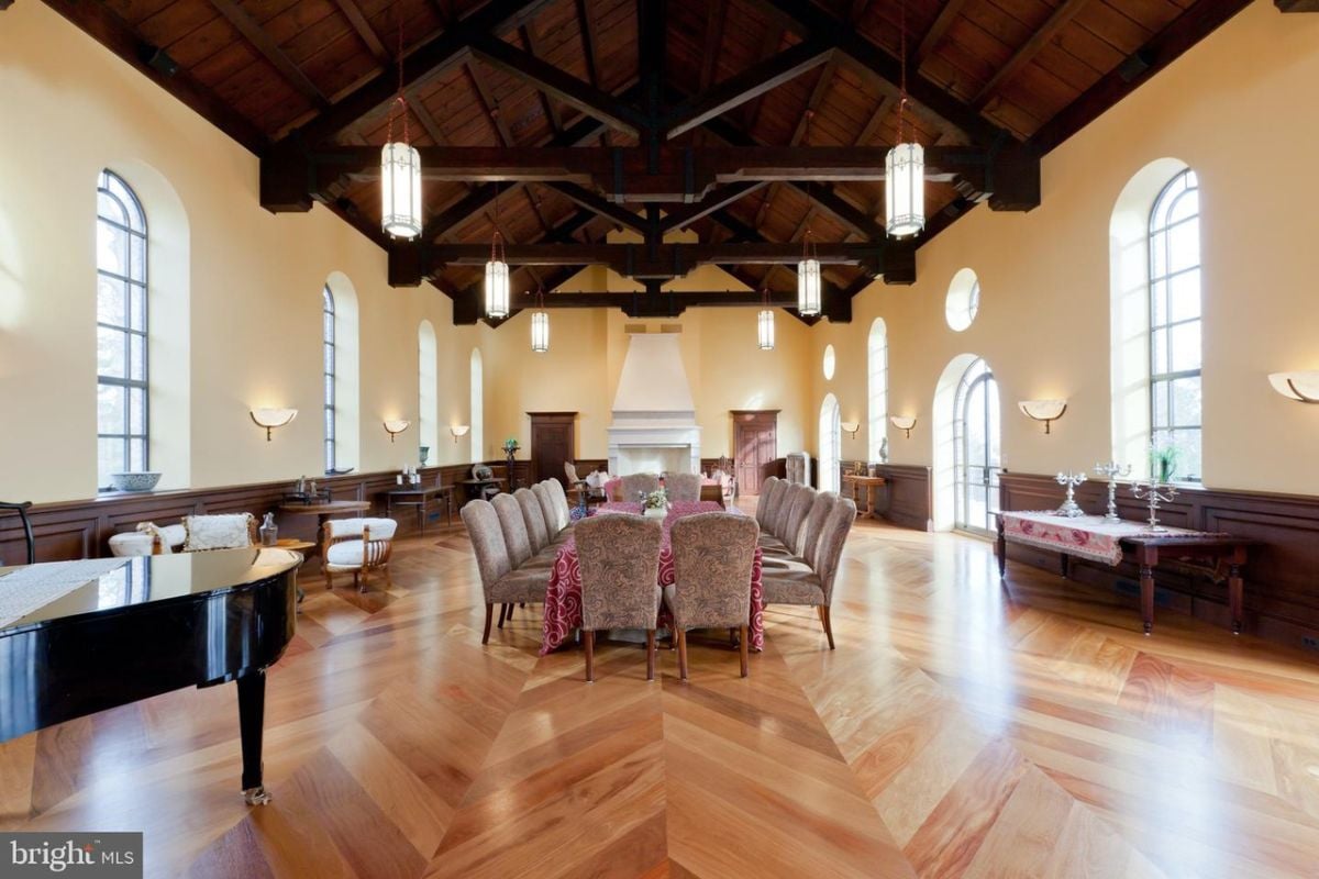 Dining room with open beam ceilings, wood flooring, a large table and chairs.