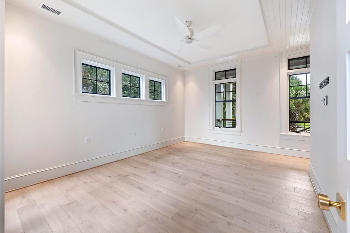 Bedroom with wood flooring, a ceiling fan and glass windows.