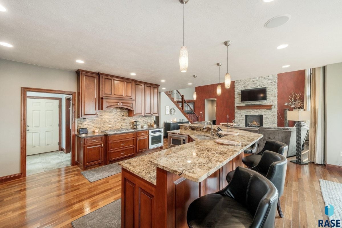 Kitchen with a large center island, wood flooring, custom cabinets and custom lights.