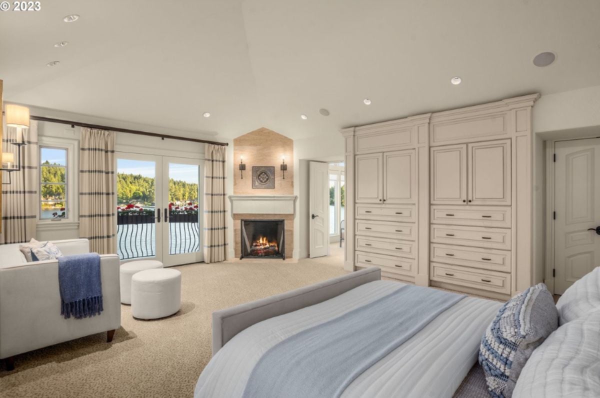 Bedroom with a bed, custom lights, glass window, glass doors, carpet flooring and a fireplace.