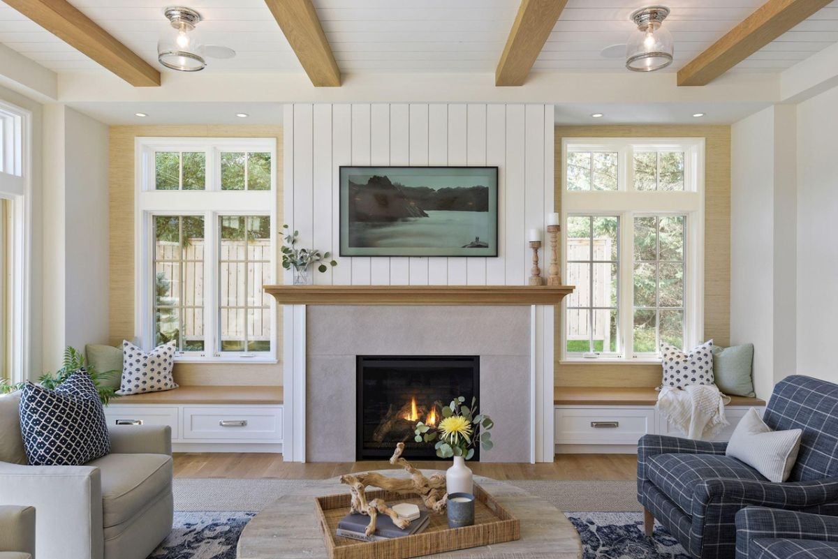 Living room with couches, glass windows and a fireplace.
