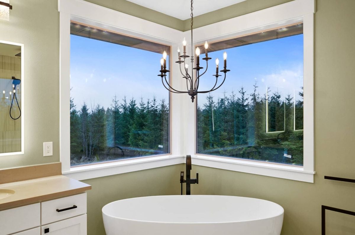 Bathroom with a soaking tub, chandelier and glass windows.