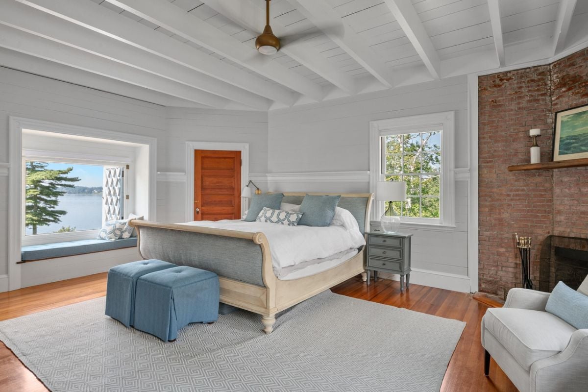 Bedroom with a large bed, ceiling fan, glass window rug and wood flooring.