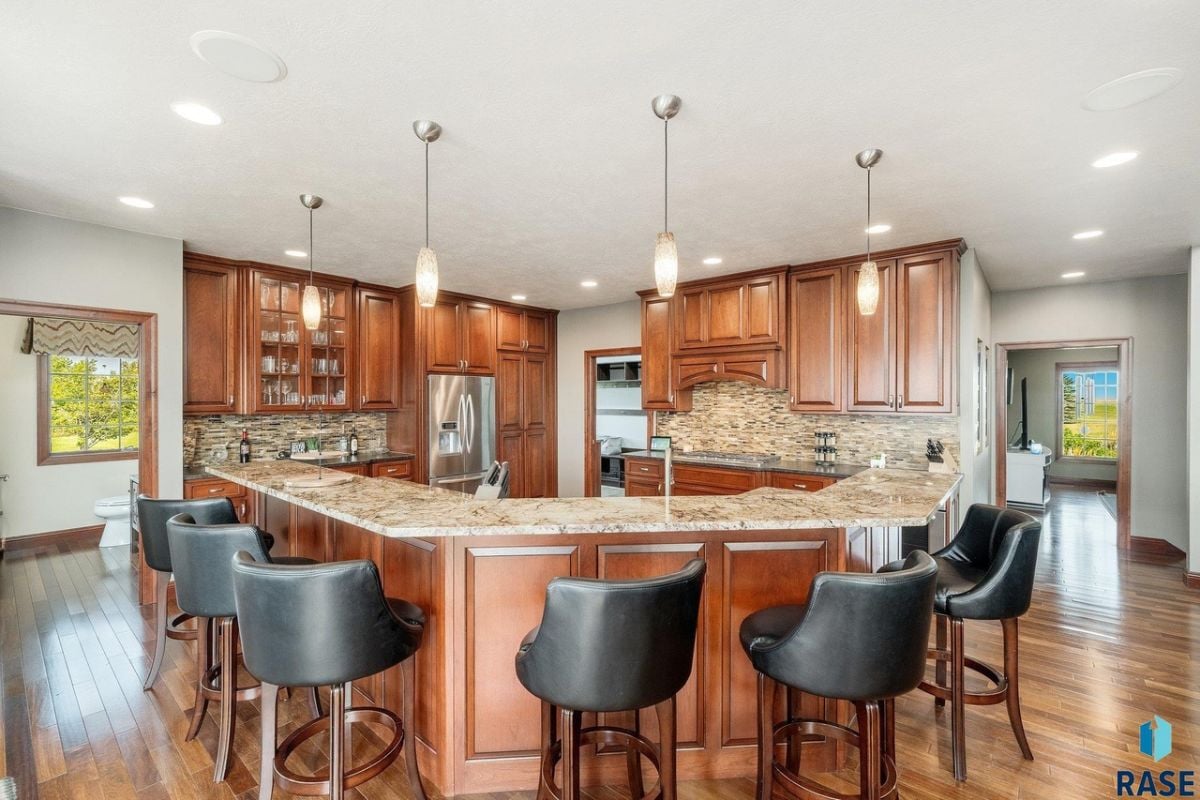 Kitchen with a large center island, wood flooring, custom cabinets and custom lights.