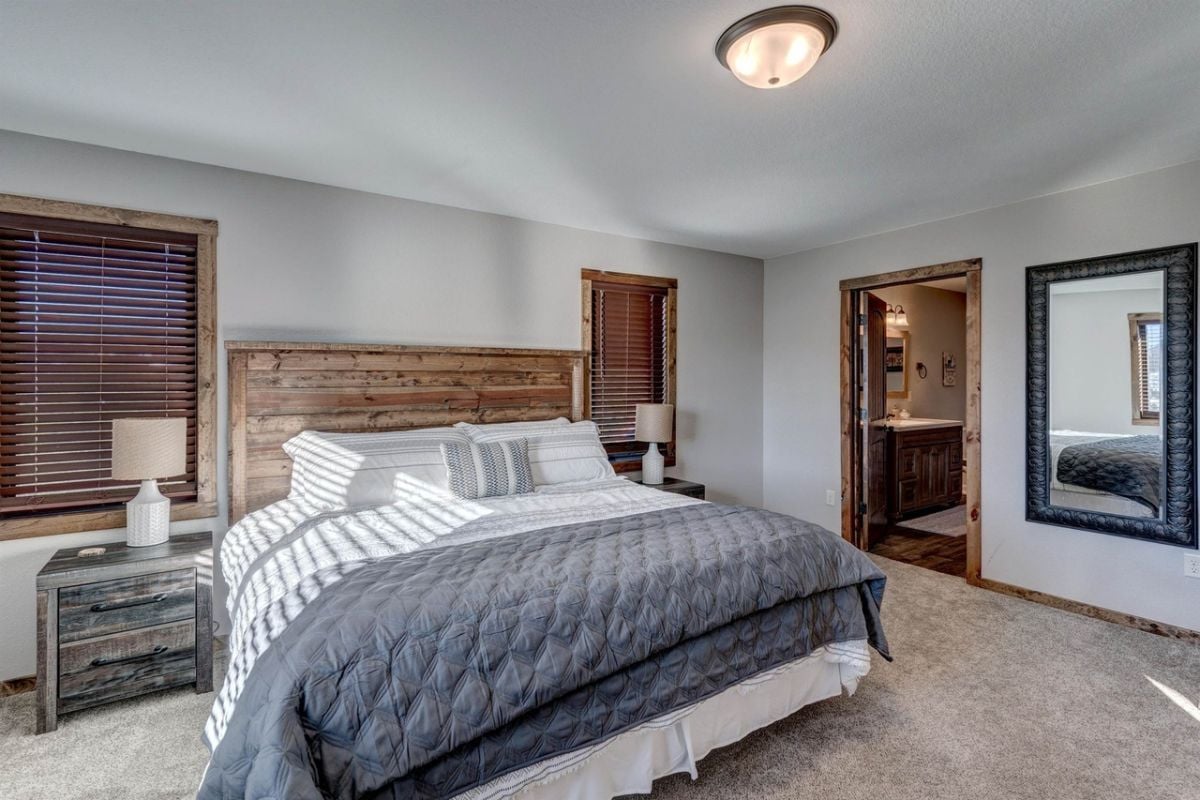 Bedroom with a large bed, carpet flooring, and a bathroom.
