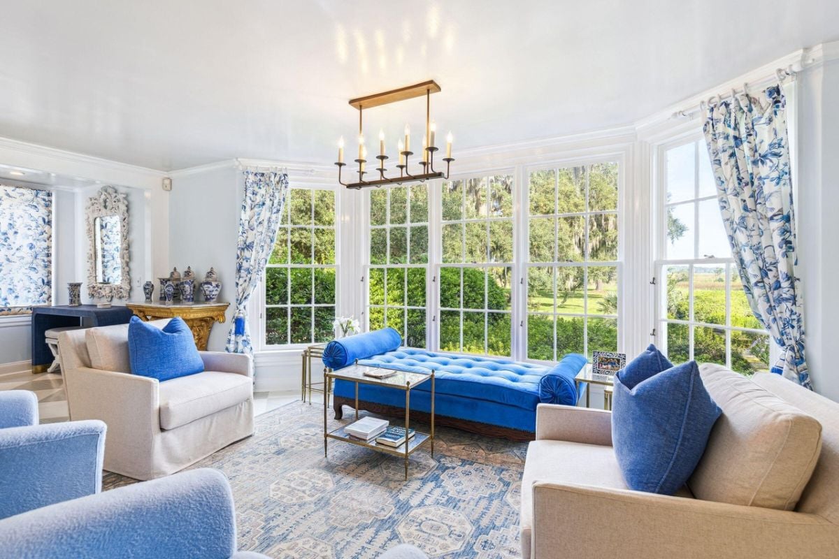 Living room with couches, a large rug and glass windows.