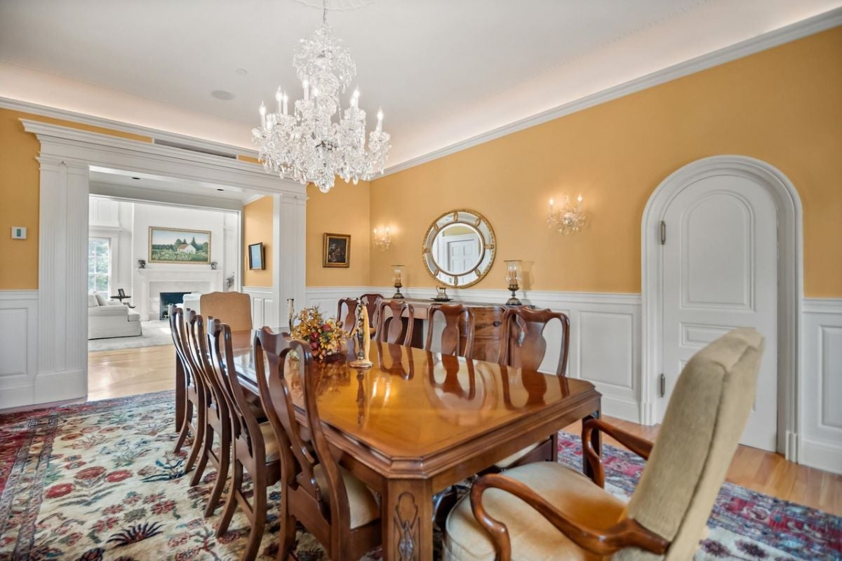 Dining room with a chandelier, a large wooden table and chairs.