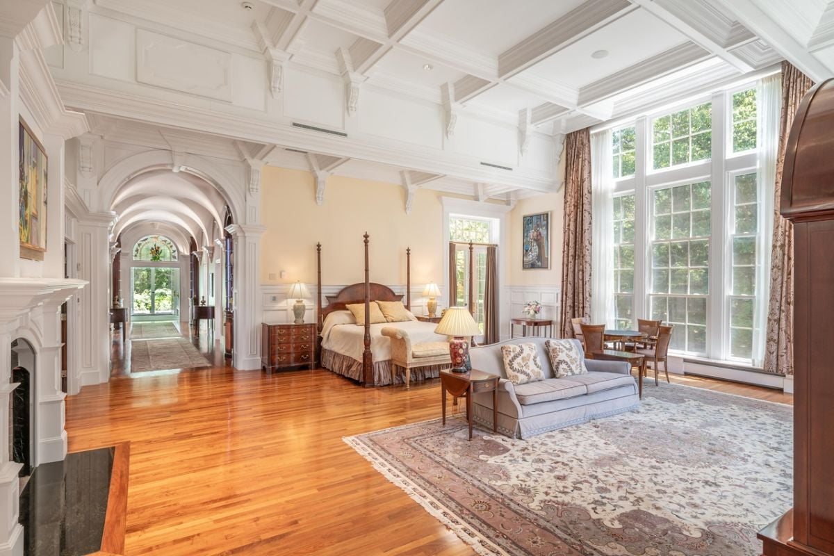 Bedroom with a large bed, couches, glass walls and a large rug.