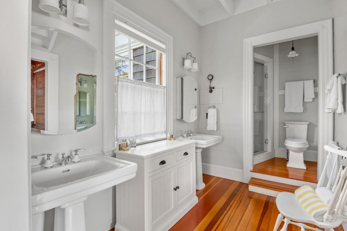 Bathroom with a toilet, dual sinks, walk-in shower and mirrors.