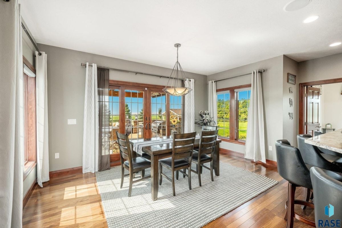 Dining room with a large wooden table, chairs and a large rug.