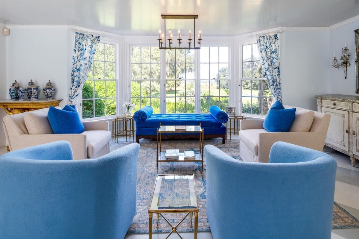 Living room with couches, a large rug and glass windows.