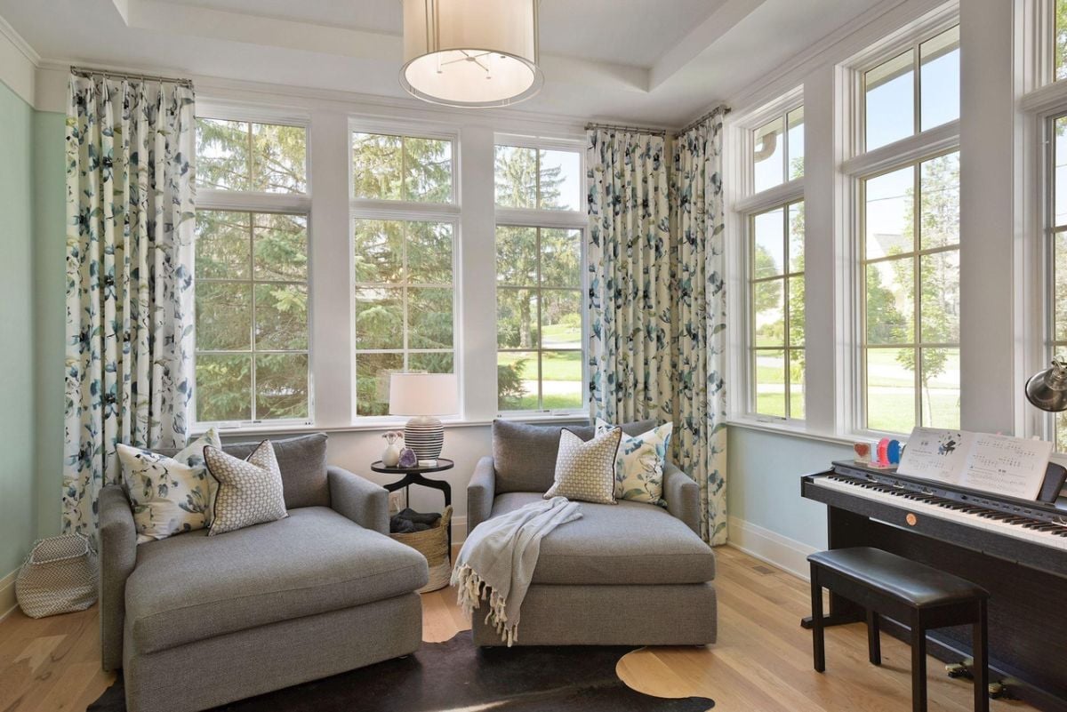 Music room with a piano, couches and glass windows.