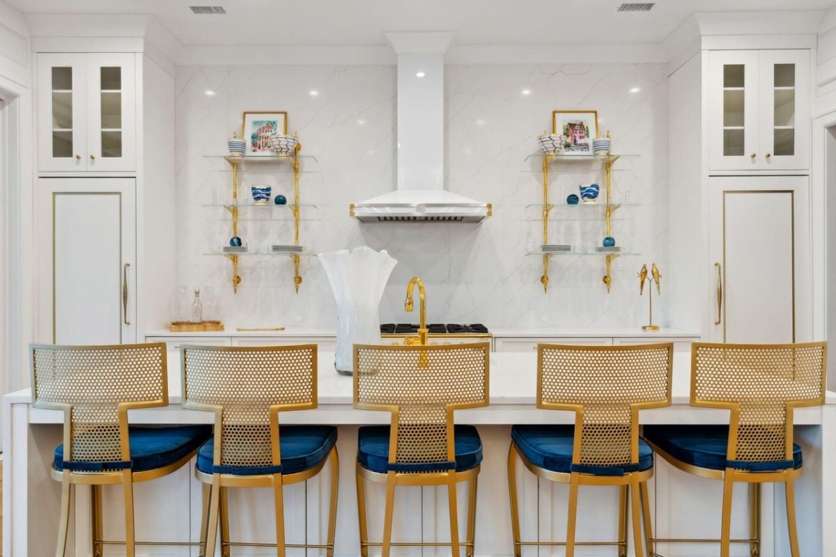 Kitchen with gold accents, a large island, custom lights and custom cabinets.