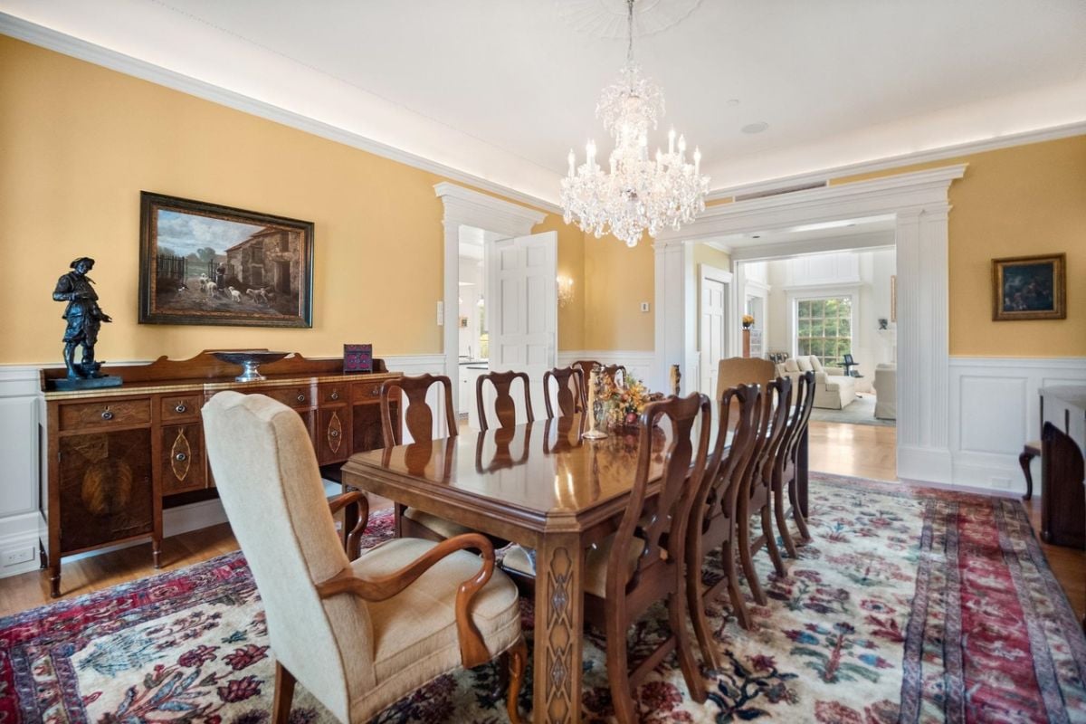Dining room with a chandelier, a large wooden table and chairs.