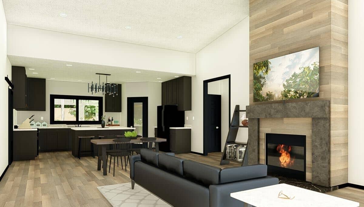 Living room and kitchen with hardwood flooring, dark wood cabinets, and a sectional sofa, and an electric fireplace.