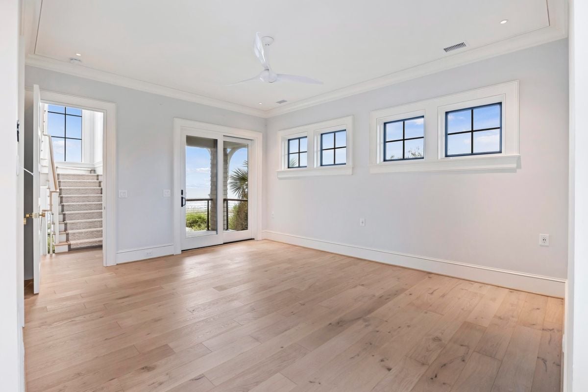 Bedroom with wood flooring, a ceiling fan and a glass door.