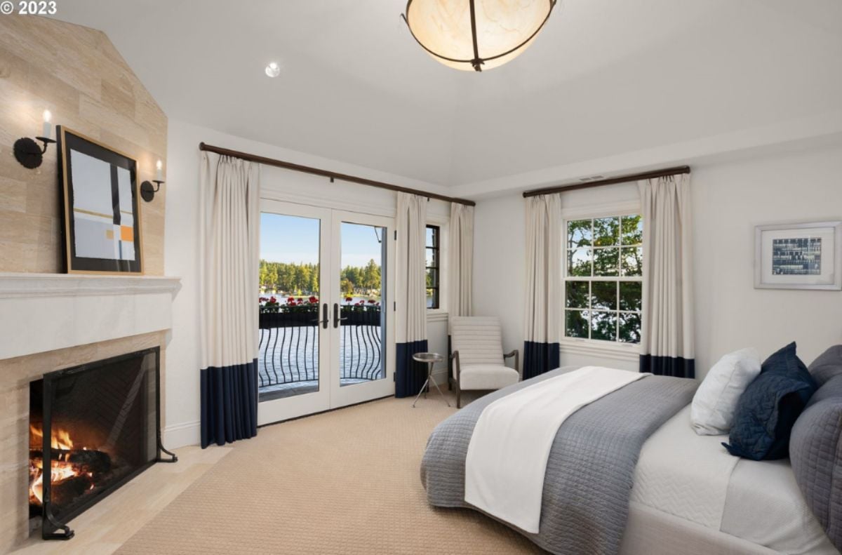 Bedroom with a bed, custom lights, glass windows, glass doors and a fireplace.