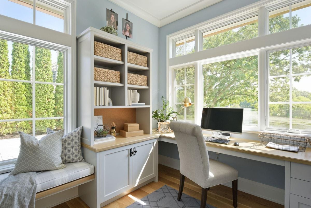 Home office with a desk, computer and glass windows.
