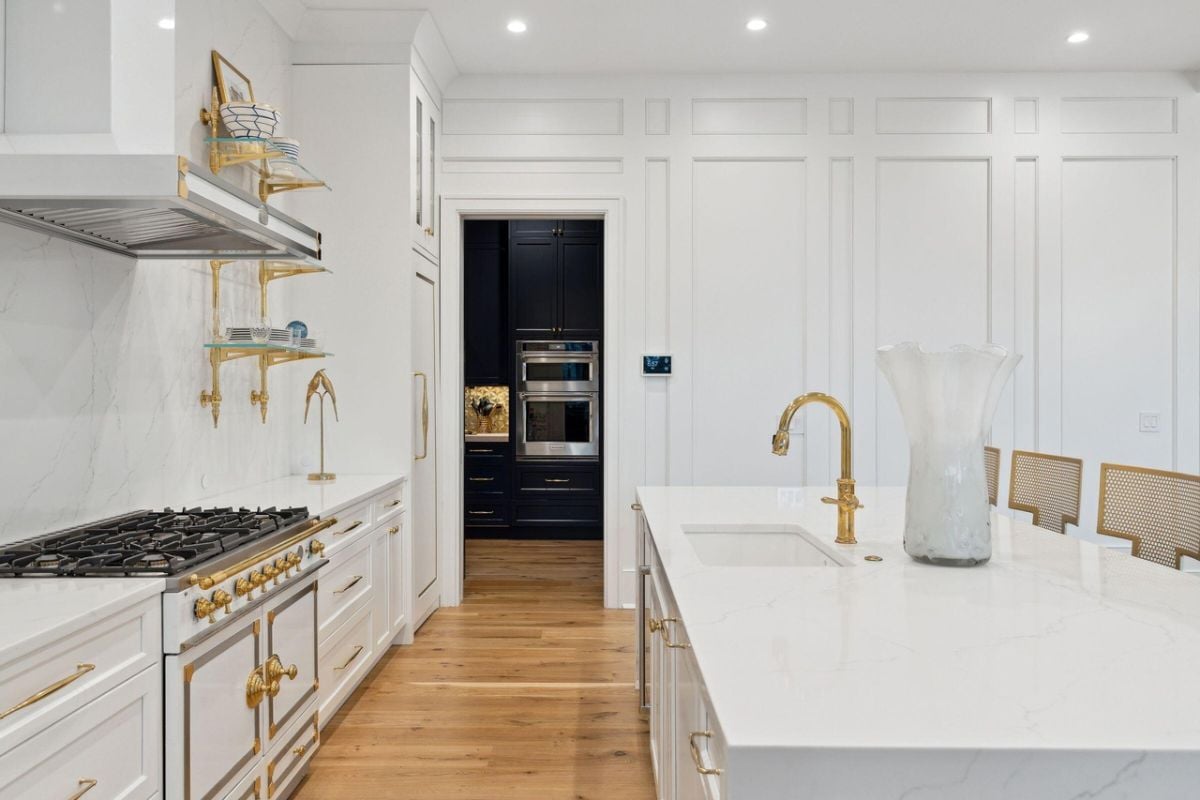 Kitchen with gold accents, a large island, custom lights and custom cabinets.
