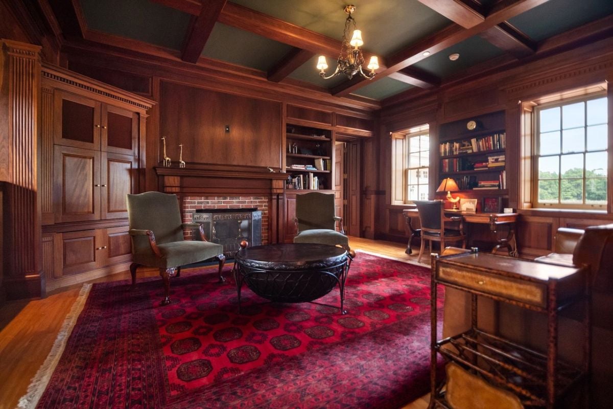 Home office with a desk, couch, wood flooring and a fireplace.