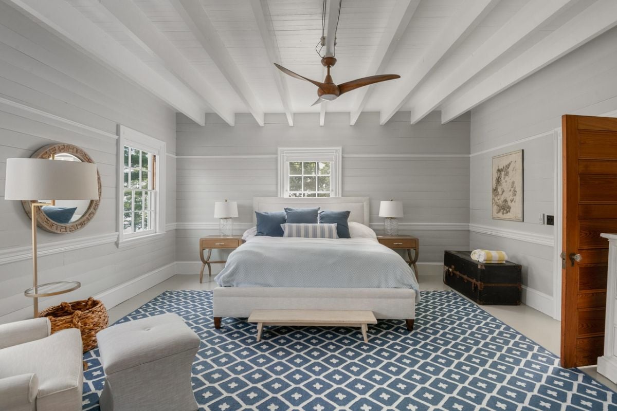 Bedroom with a large bed, ceiling fan, glass window and a large rug.