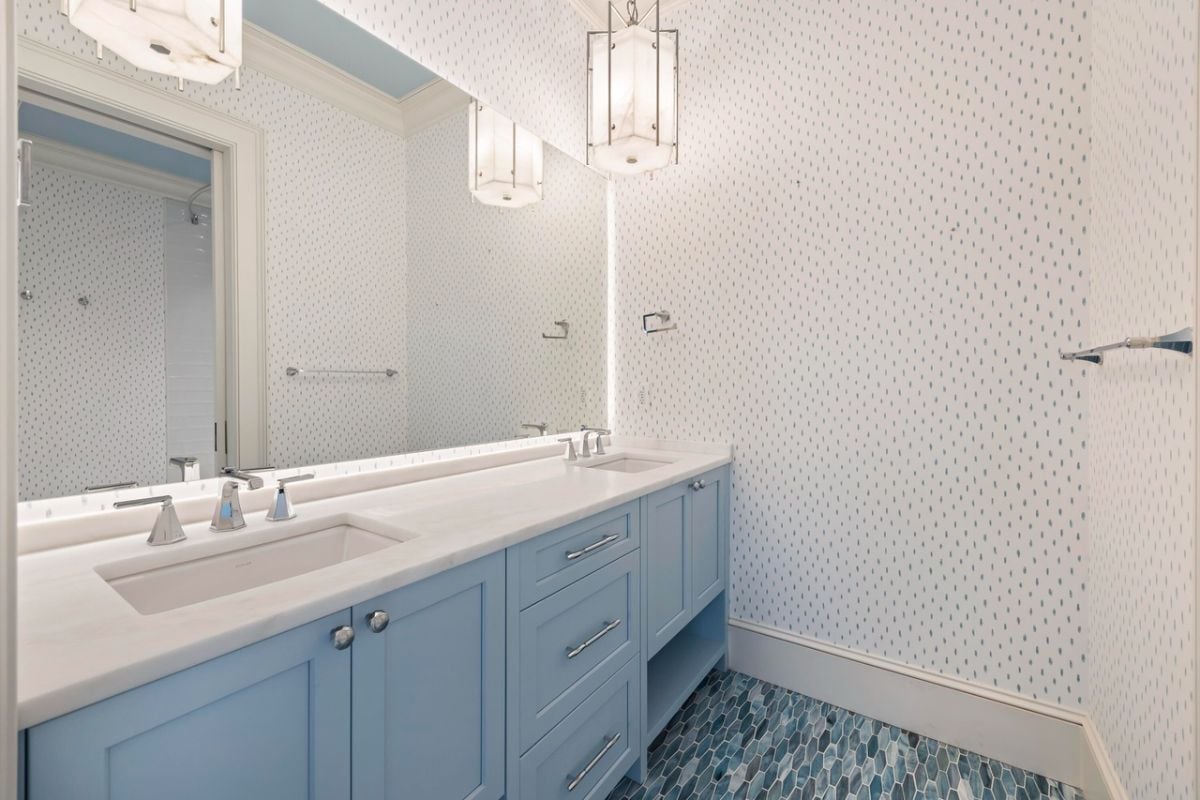 Bathroom with dual sinks, a large mirror and custom lights.