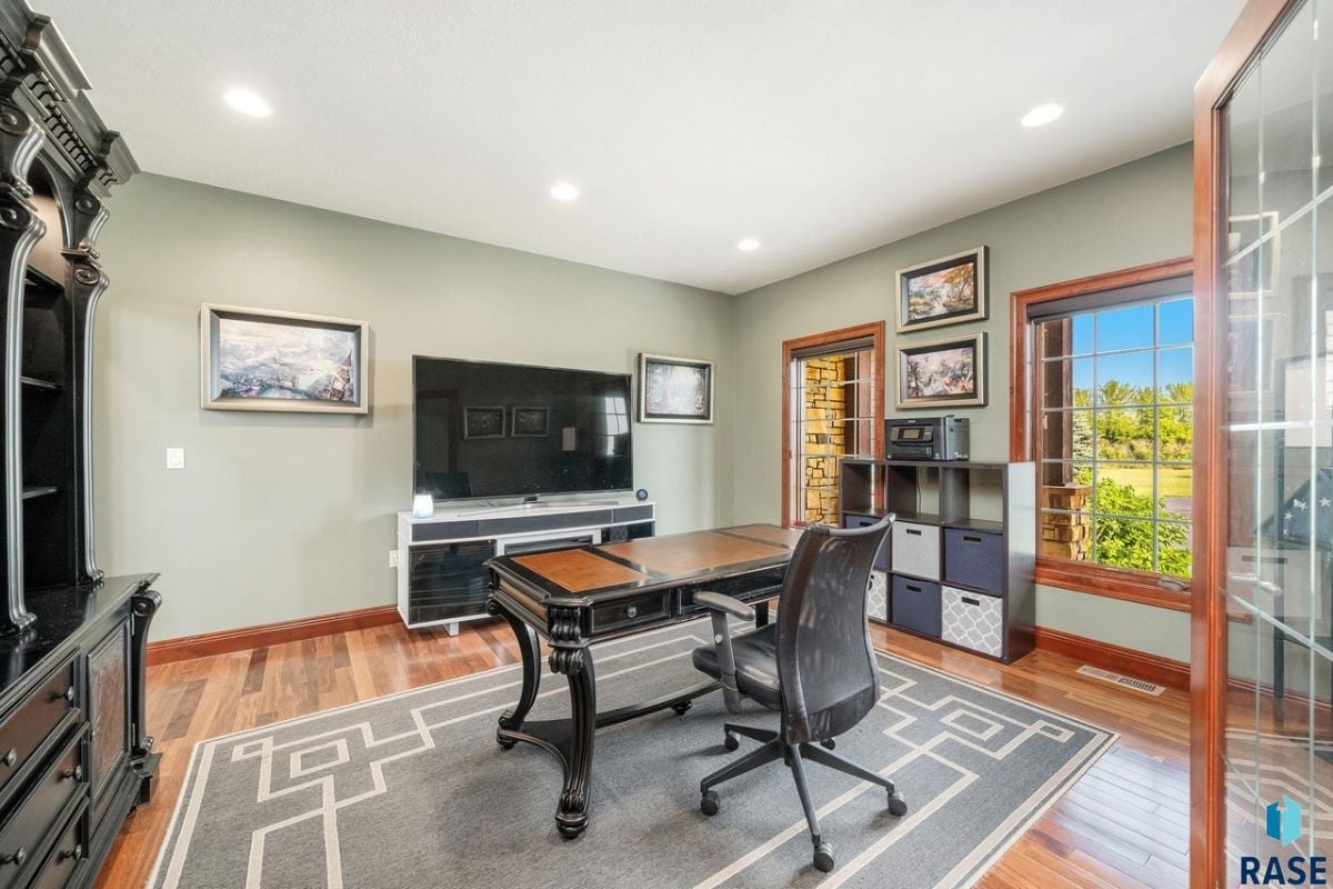 Home office with a desk, chair and a TV.