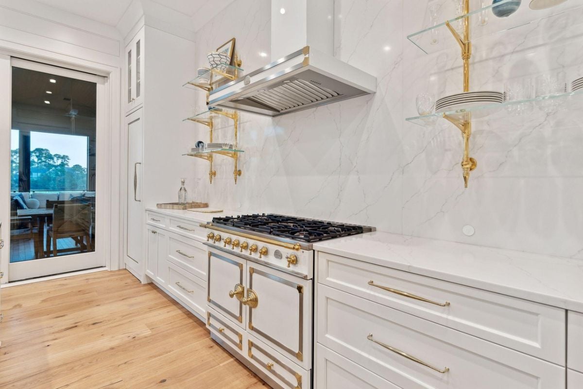 Kitchen with gold accents, a large island, custom lights and custom cabinets.