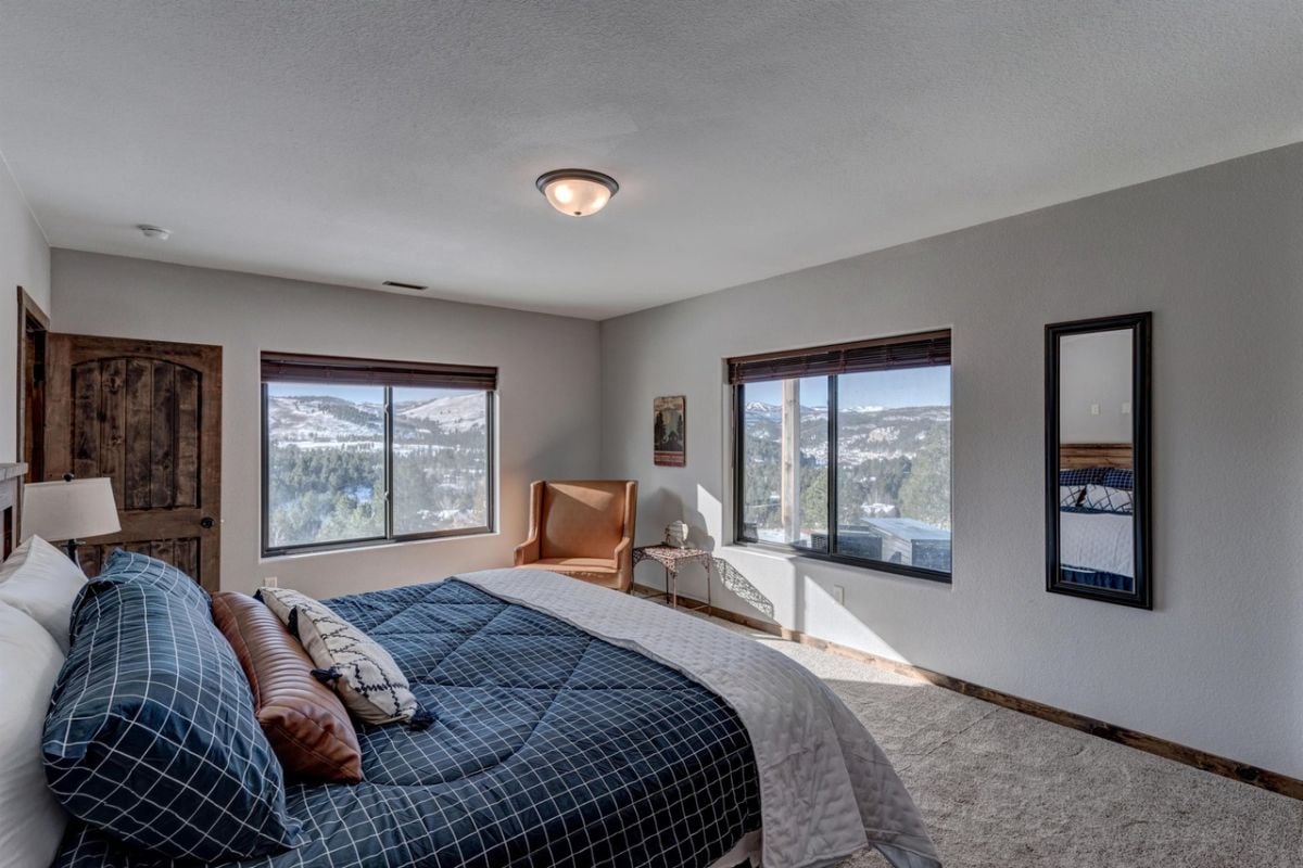 Bedroom with a large bed, carpet flooring, and glass windows.