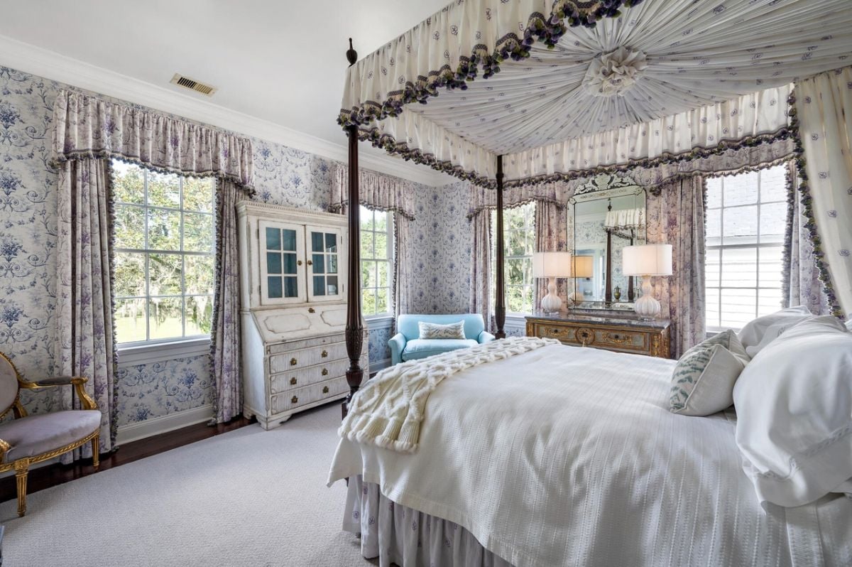 Bedroom with a large bed, carpet flooring, couch and glass windows.
