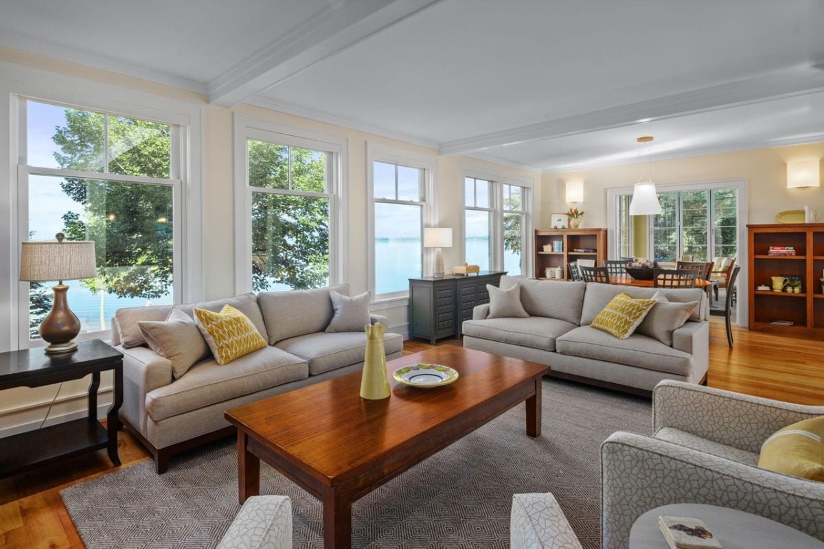 Living room with couches, wooden table and glass windows.
