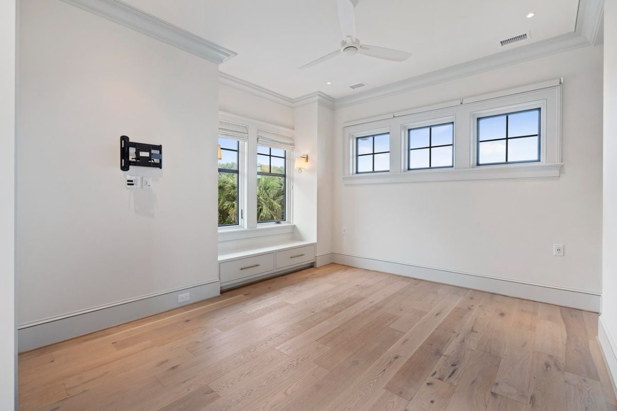 Bedroom with wood flooring, a ceiling fan and a glass windows.