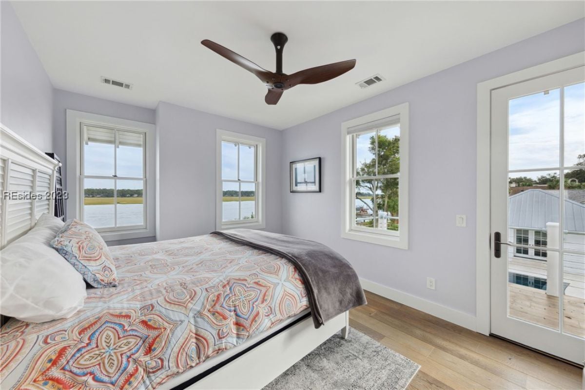 Bedroom with a large bed, wood flooring, glass door and a balcony.