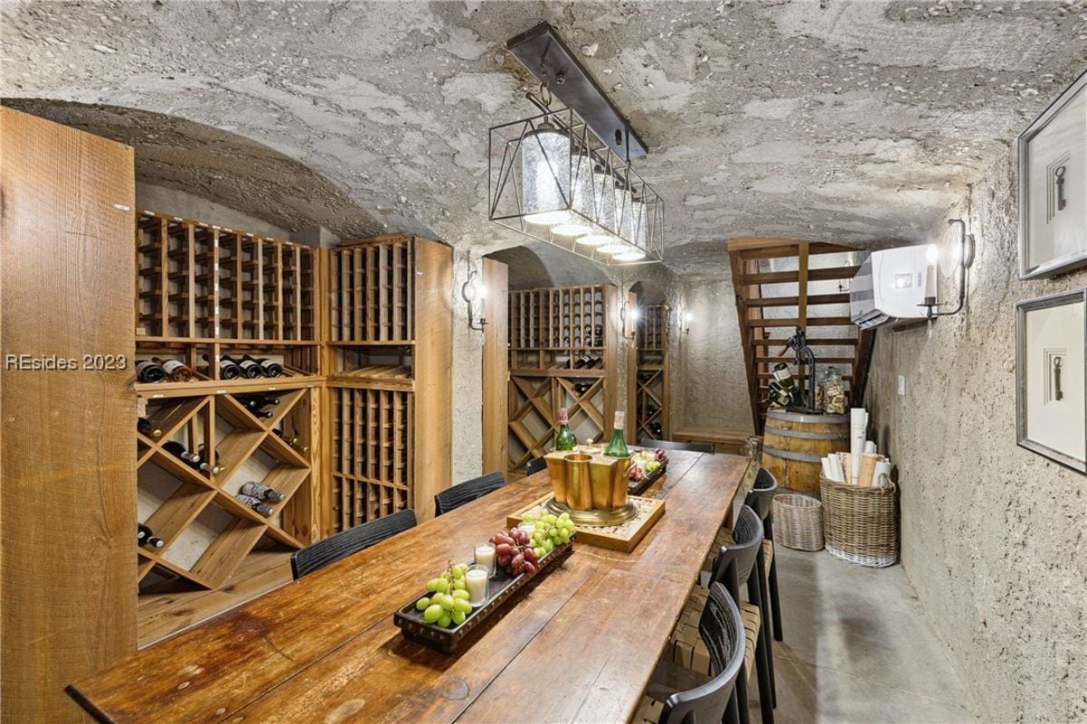 Wine cellar with a large wooden table, chairs and wine racks.
