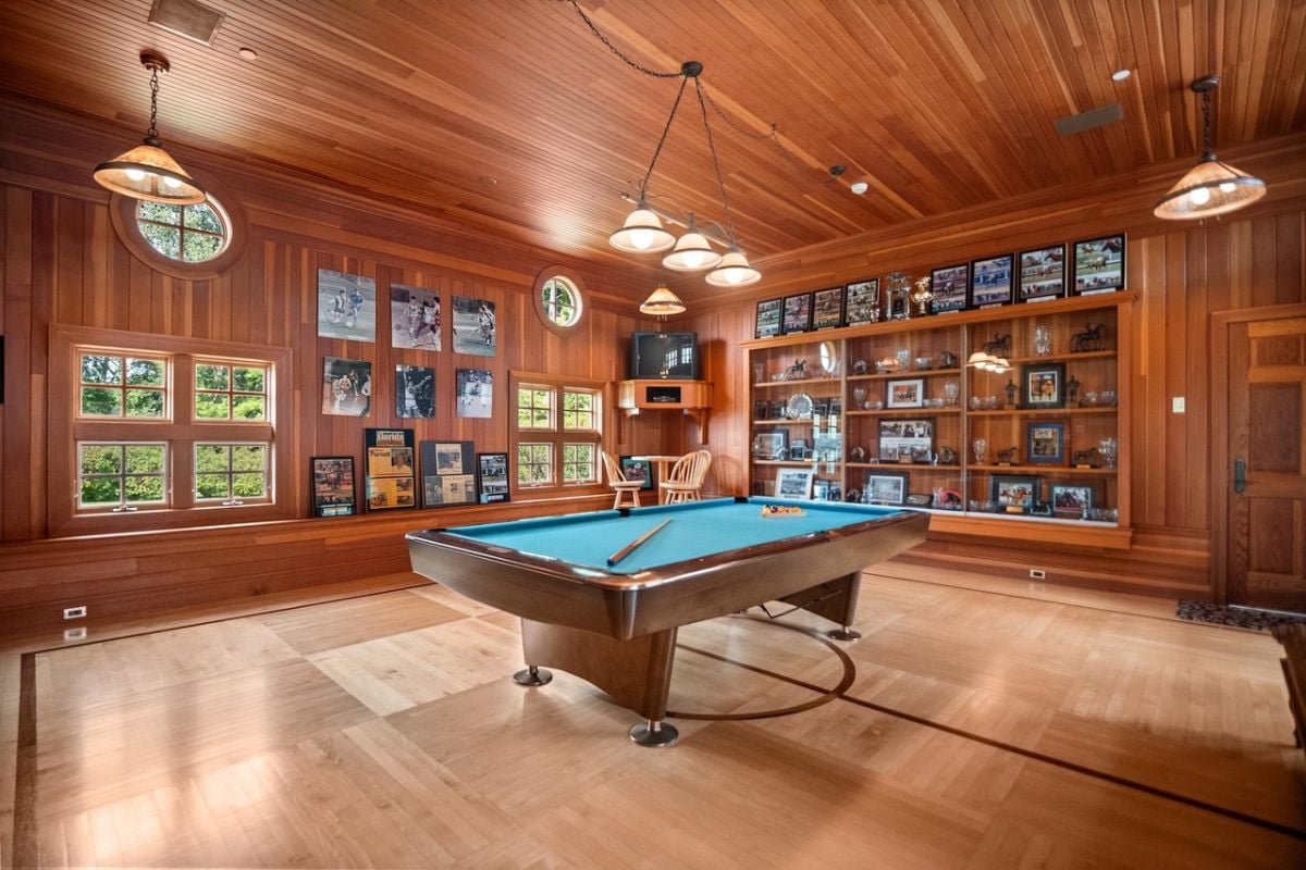 Billiards room with custom lights, wooden floor and glass windows.