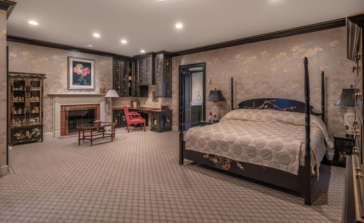 Bedroom with a large bed, custom lights, fireplace and carpet flooring.