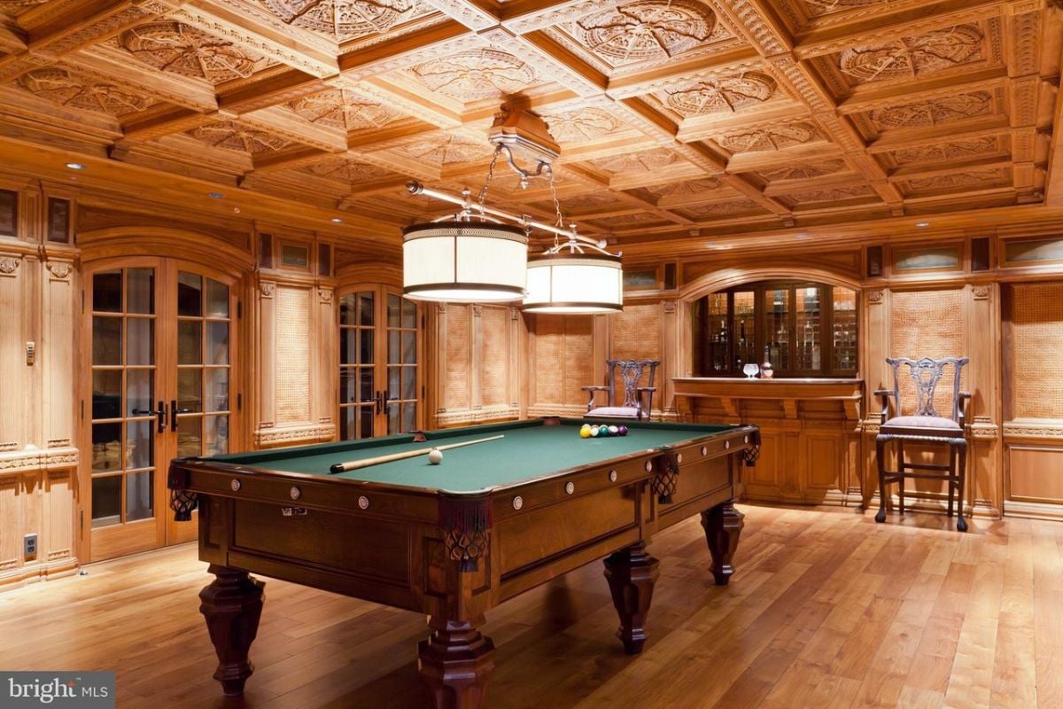 Billiards room with with wooden floors and a bar.