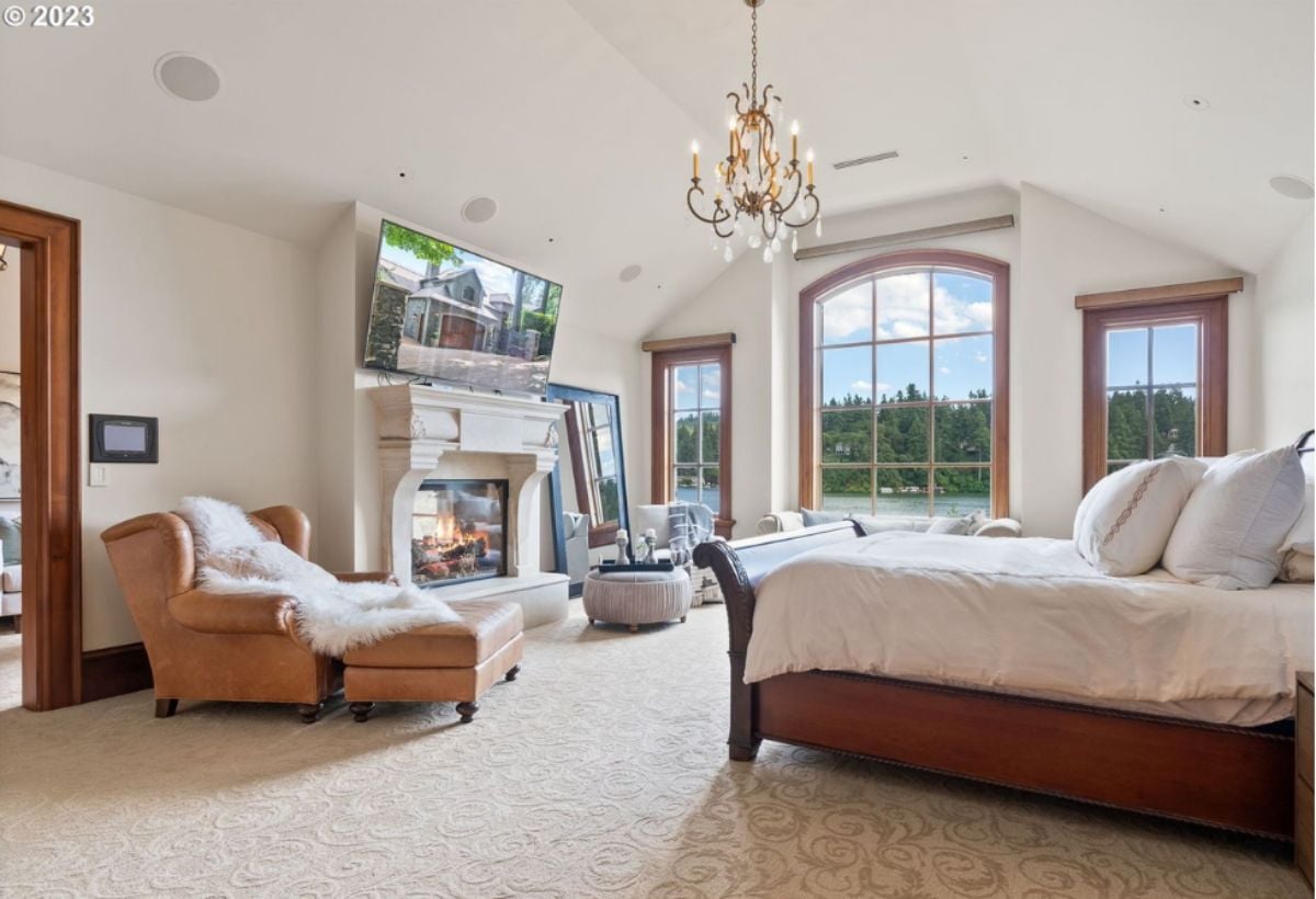 Bedroom with large bed, TV, chandelier and a fireplace.