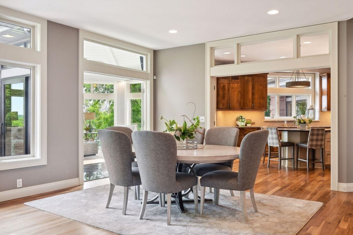 Dining room with wooden floors, a large rug, a large table and chairs.