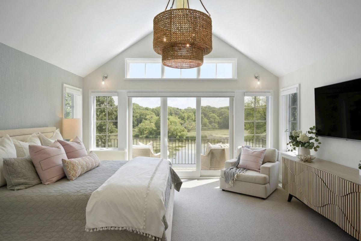 Bedroom with a large bed, carpet flooring, glass doors and a balcony.