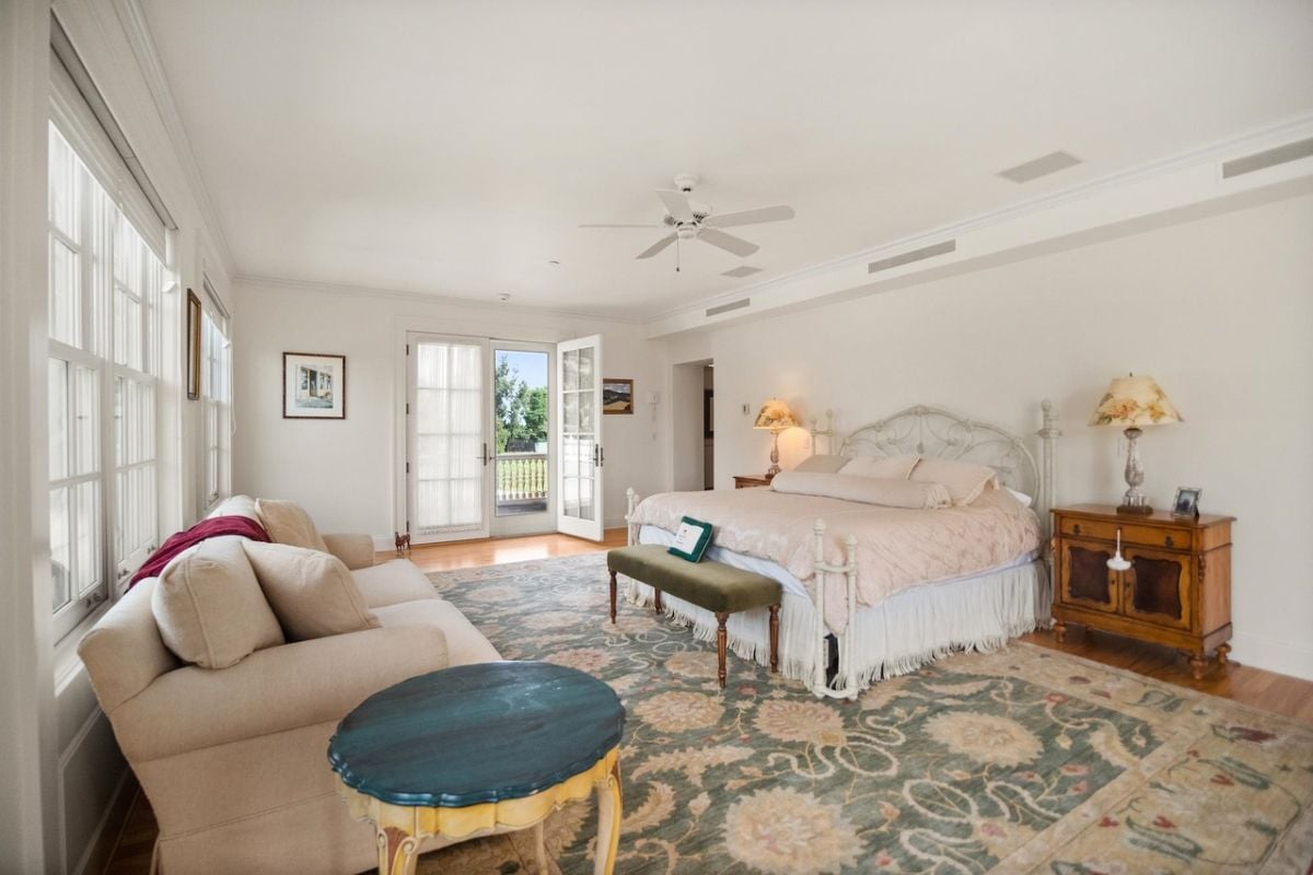 Bedroom with a large bed, couch, a large rug and glass door.