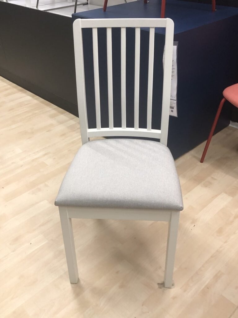 White IKEA dining room chair with a gray cushioned seat in the IKEA showroom