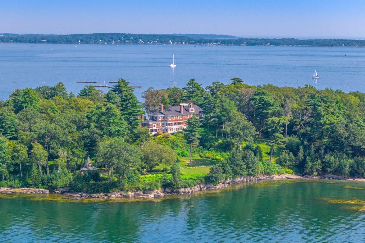 Aerial view of the house with ocean shore and trees.