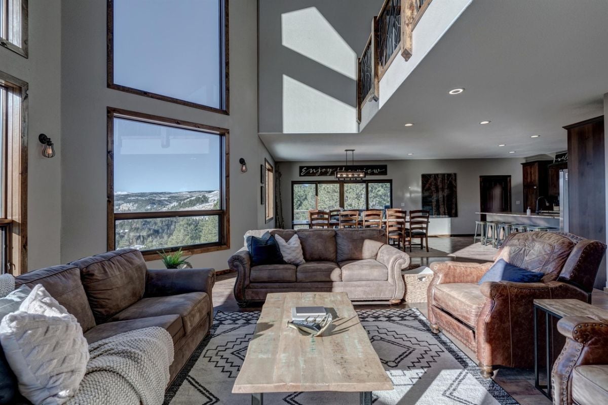 Living room with couches, a large rug and glass wall windows.