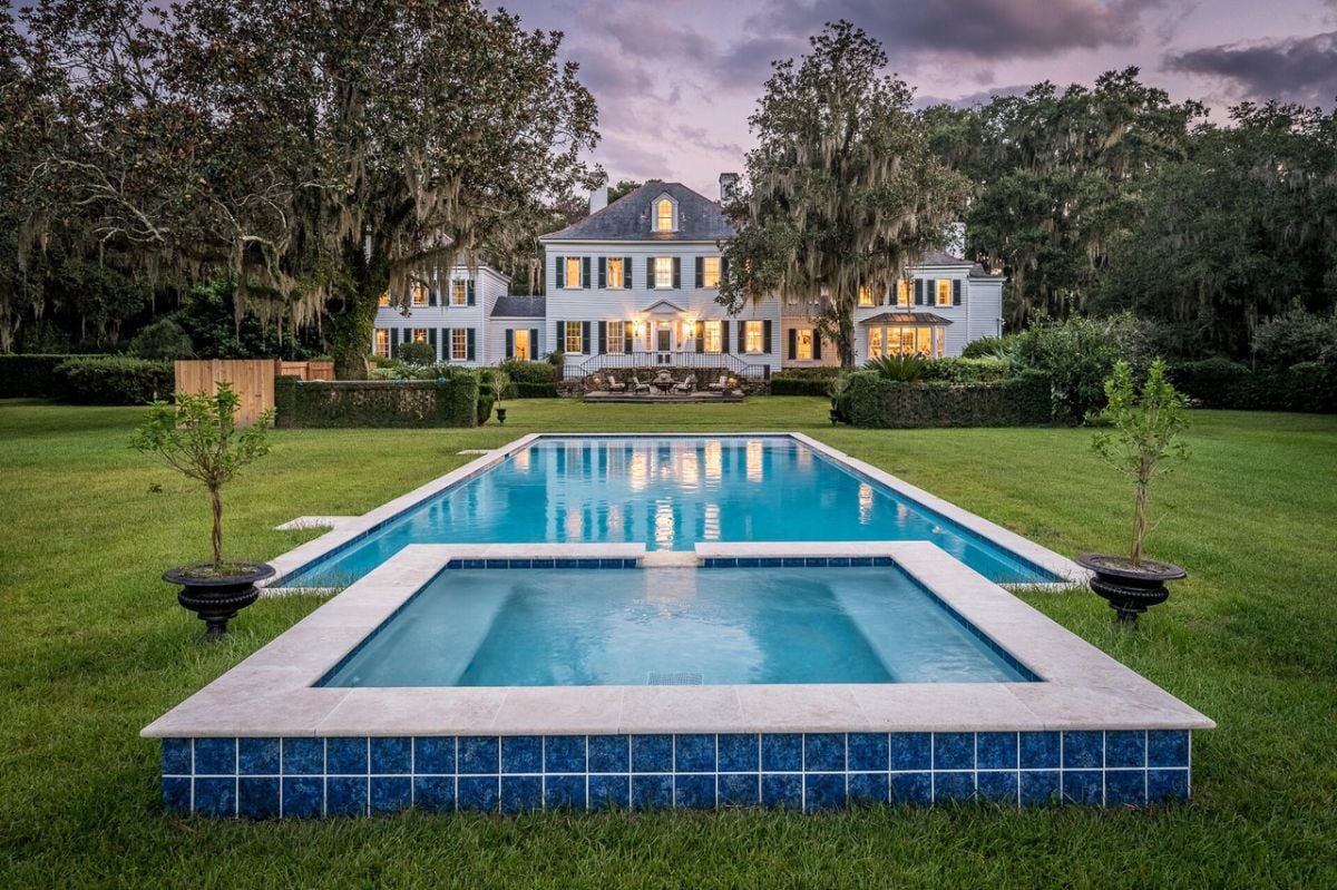 Rear view of the house with a pool and a large green lawn.