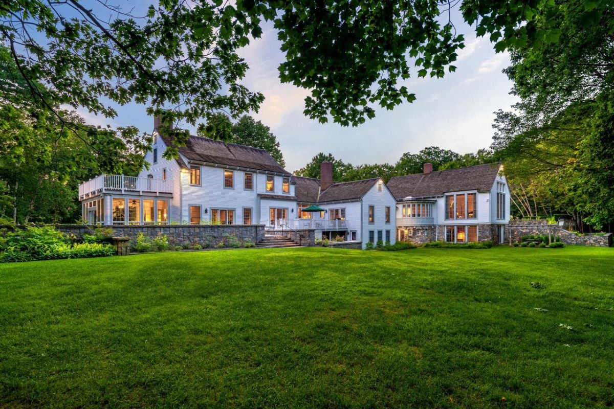 Rear view of the house with a green lawn and trees.